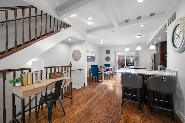 kitchen with decorative light fixtures, stainless steel fridge, dark hardwood / wood-style floors, kitchen peninsula, and beam ceiling