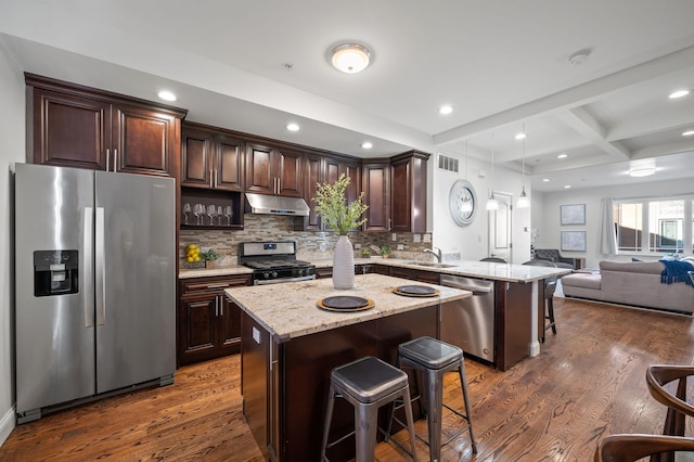 kitchen with a center island, stainless steel appliances, beamed ceiling, a breakfast bar, and coffered ceiling