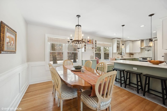 dining area featuring sink, light hardwood / wood-style floors, plenty of natural light, and a notable chandelier