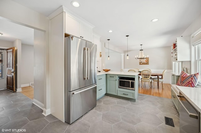 kitchen featuring light tile patterned floors, white cabinetry, appliances with stainless steel finishes, hanging light fixtures, and green cabinetry