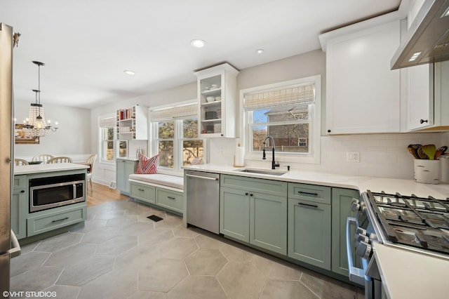 kitchen featuring pendant lighting, sink, green cabinetry, stainless steel appliances, and white cabinets