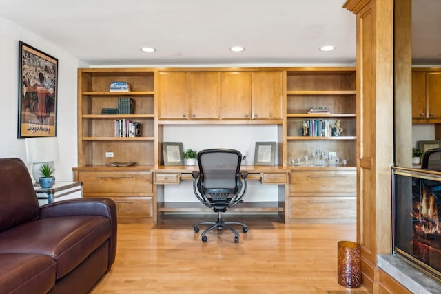 office space with built in desk and light hardwood / wood-style flooring