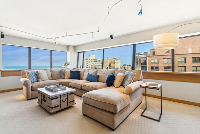 living room with light colored carpet, rail lighting, and a water view