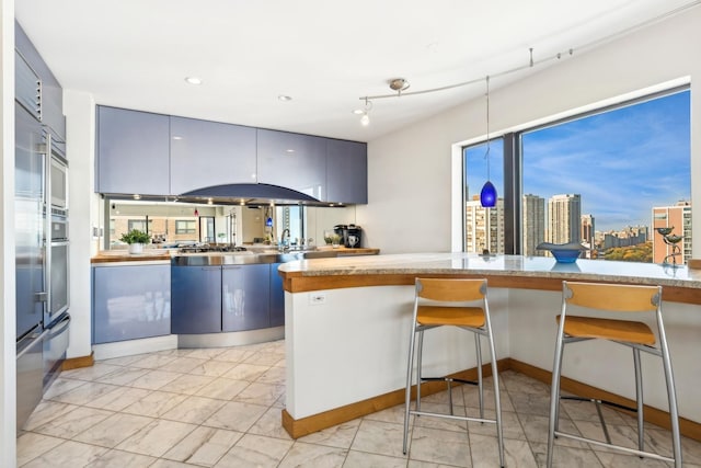 kitchen with decorative light fixtures, kitchen peninsula, a breakfast bar, and plenty of natural light