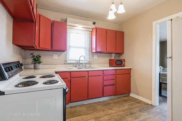 kitchen featuring pendant lighting, light hardwood / wood-style floors, sink, and white range with electric stovetop