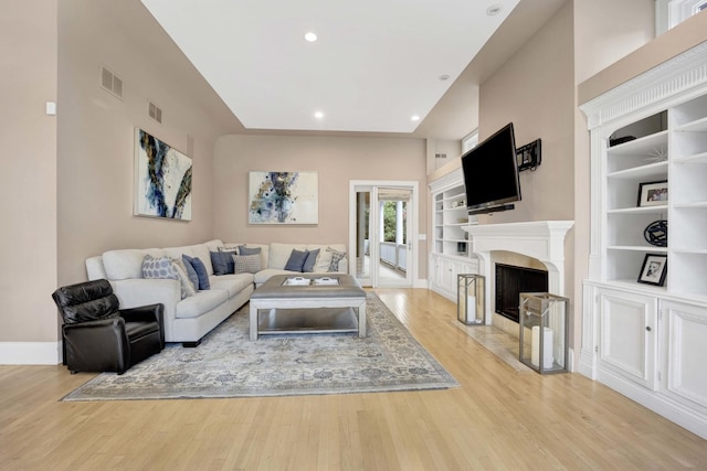 living room with built in shelves and light hardwood / wood-style floors