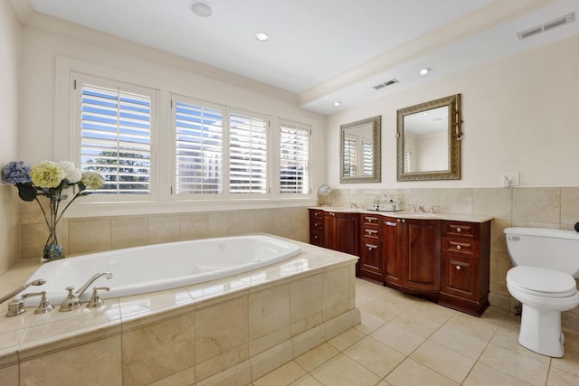 bathroom with tile patterned floors, tiled bath, vanity, and toilet