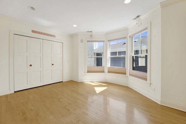 unfurnished bedroom featuring crown molding, light hardwood / wood-style flooring, and a closet