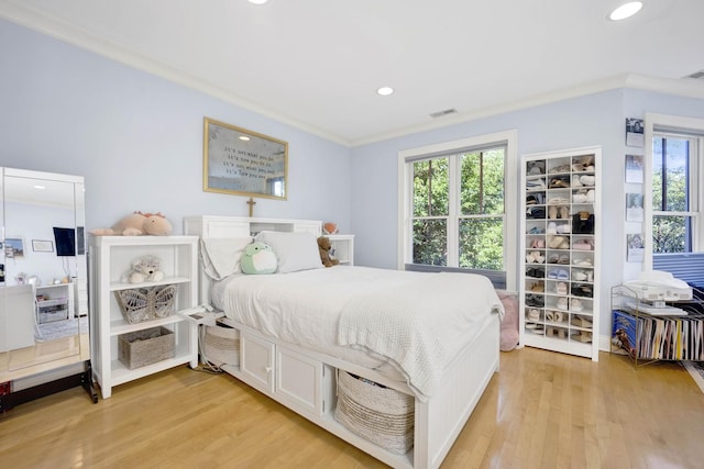 bedroom with light hardwood / wood-style floors, crown molding, and multiple windows