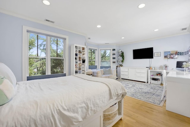 bedroom featuring light wood-type flooring, multiple windows, and ornamental molding