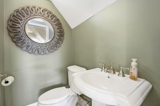 bathroom featuring toilet, lofted ceiling, and sink