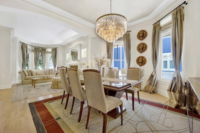 dining area featuring ornate columns, crown molding, light hardwood / wood-style flooring, and a chandelier