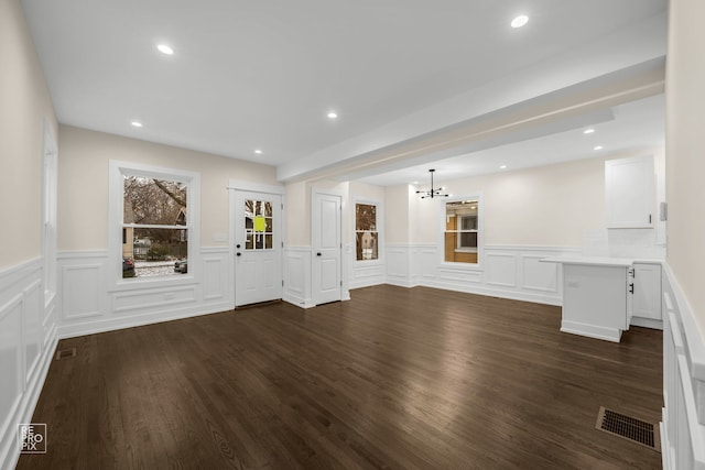 unfurnished living room featuring dark hardwood / wood-style floors and a notable chandelier