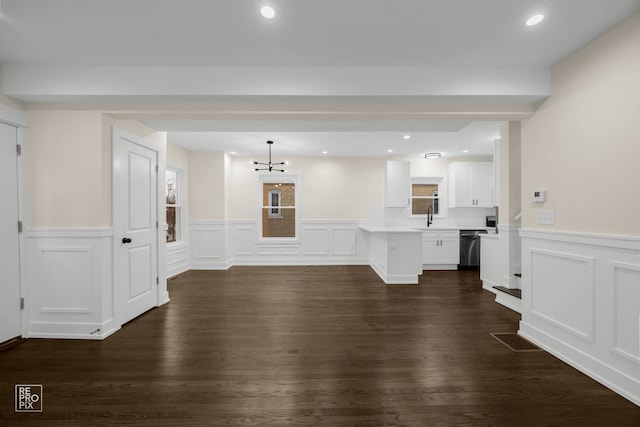 unfurnished living room featuring an inviting chandelier, sink, and dark wood-type flooring