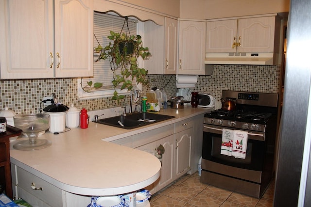 kitchen featuring gas stove, decorative backsplash, sink, and light tile patterned flooring