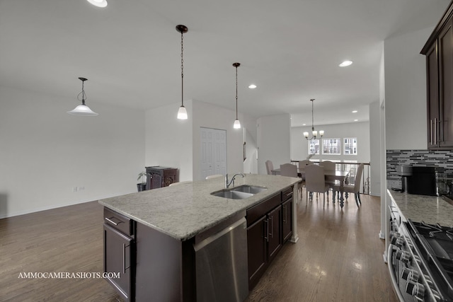 kitchen with dark brown cabinetry, sink, decorative light fixtures, stainless steel appliances, and a kitchen island with sink