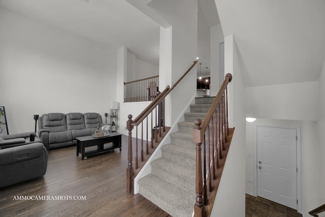 stairway with hardwood / wood-style flooring and high vaulted ceiling