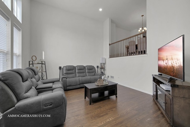 living room with a high ceiling, a chandelier, and dark hardwood / wood-style flooring