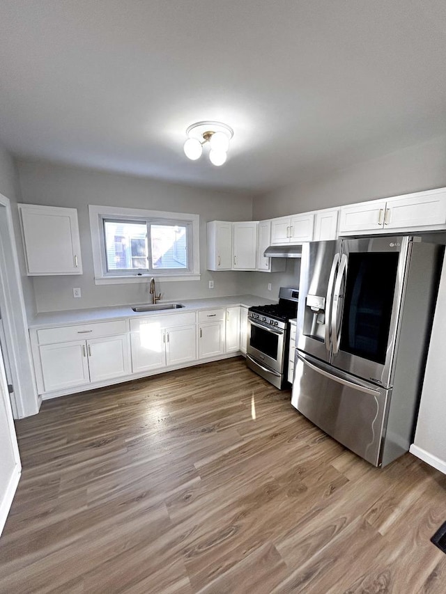 kitchen with sink, stainless steel appliances, white cabinetry, and light hardwood / wood-style floors