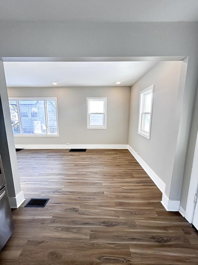 spare room featuring a wealth of natural light and dark hardwood / wood-style floors