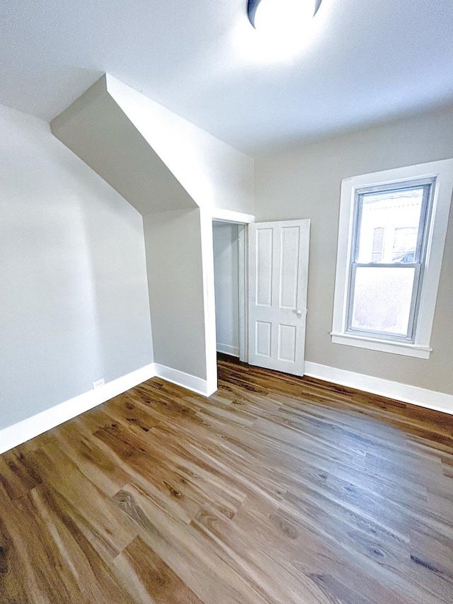 additional living space with hardwood / wood-style flooring and vaulted ceiling