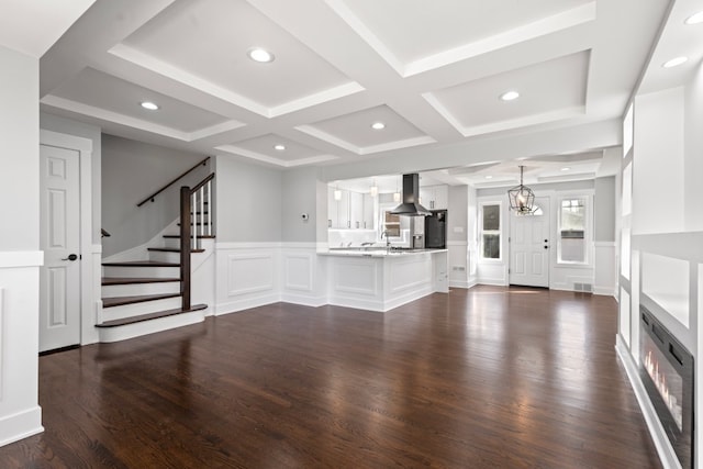 unfurnished living room with beam ceiling, sink, coffered ceiling, an inviting chandelier, and dark hardwood / wood-style flooring