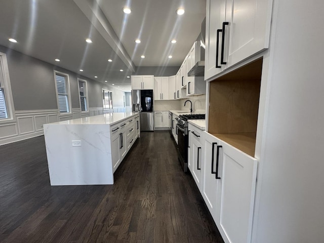 kitchen featuring white cabinets, stainless steel appliances, a kitchen island, and light stone counters