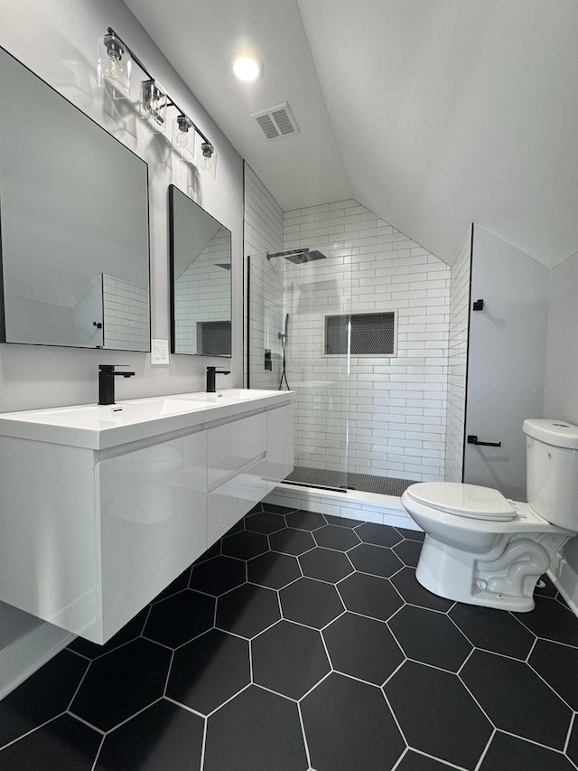 bathroom with vanity, lofted ceiling, tile patterned floors, toilet, and tiled shower