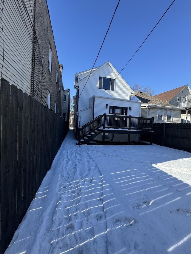 snow covered rear of property featuring a wooden deck