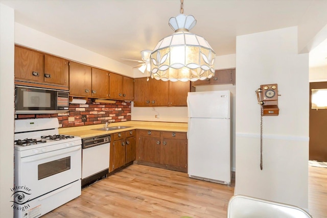 kitchen with sink, white appliances, ceiling fan, light wood-type flooring, and hanging light fixtures