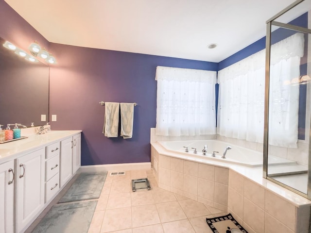 bathroom with tile patterned flooring, vanity, and tiled tub