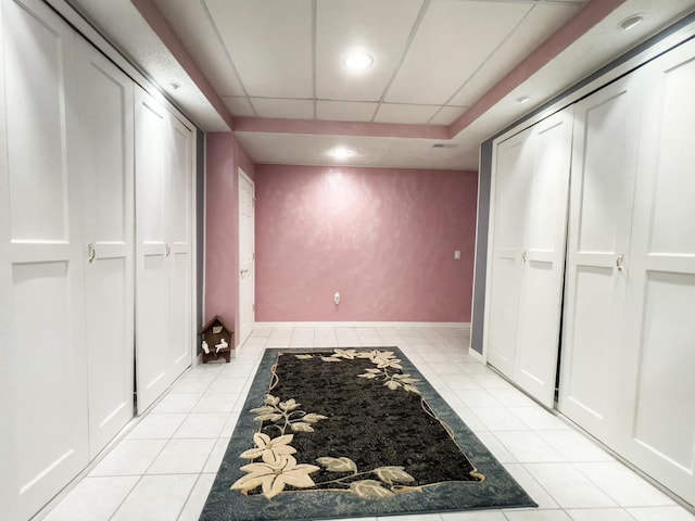 hallway with a drop ceiling and light tile patterned floors