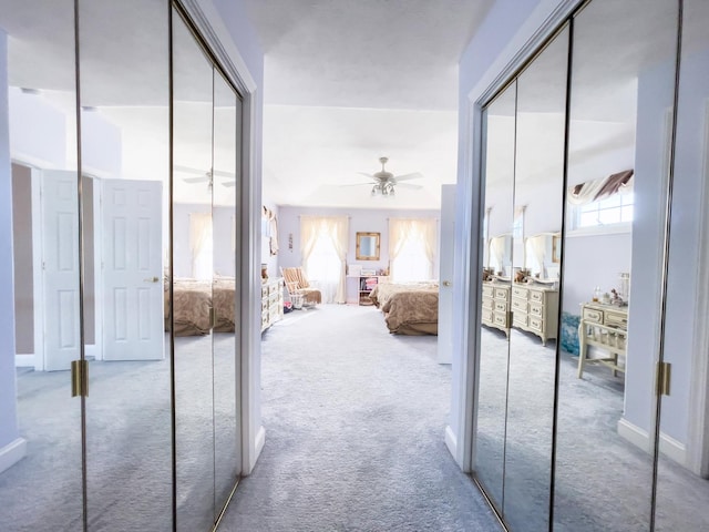 bedroom featuring carpet floors, two closets, ceiling fan, and multiple windows