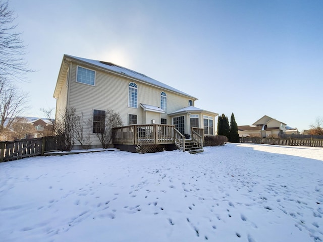 snow covered rear of property with a wooden deck