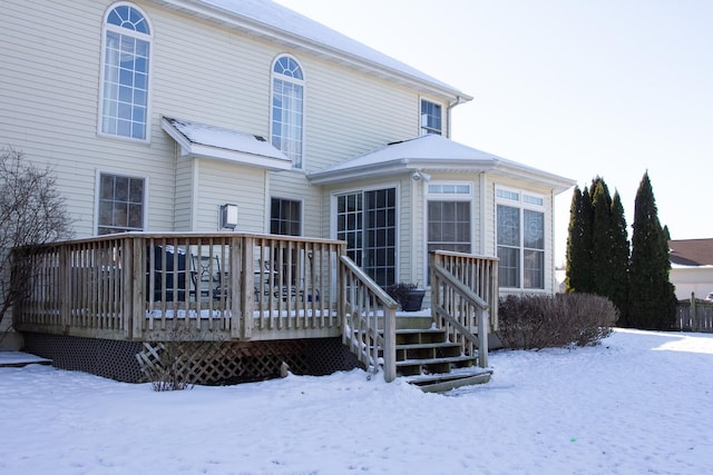 snow covered back of property with a wooden deck