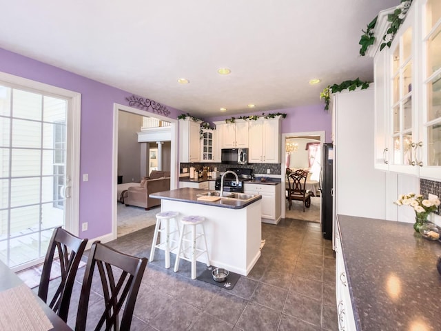 kitchen featuring sink, white cabinetry, a kitchen bar, backsplash, and a center island with sink