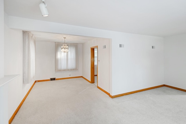 spare room with light colored carpet and a notable chandelier