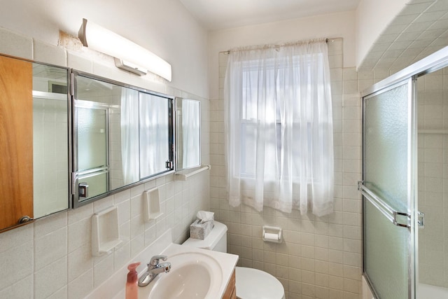 bathroom with a shower with shower door, tile walls, toilet, and vanity