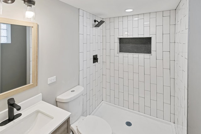 bathroom with tiled shower, vanity, and toilet