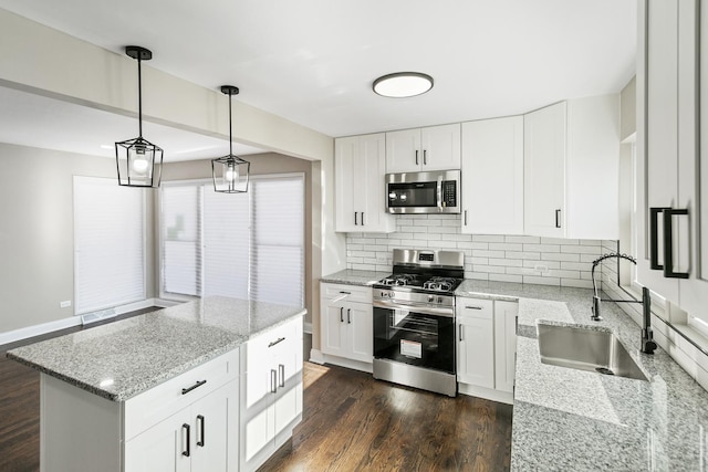 kitchen with light stone counters, stainless steel appliances, hanging light fixtures, and white cabinetry