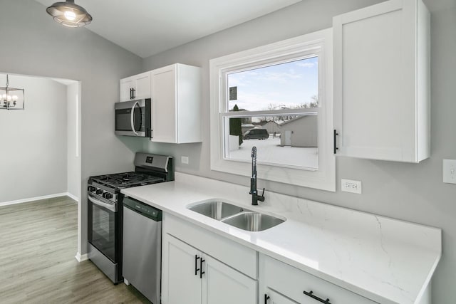 kitchen featuring a chandelier, appliances with stainless steel finishes, light wood-type flooring, sink, and white cabinetry