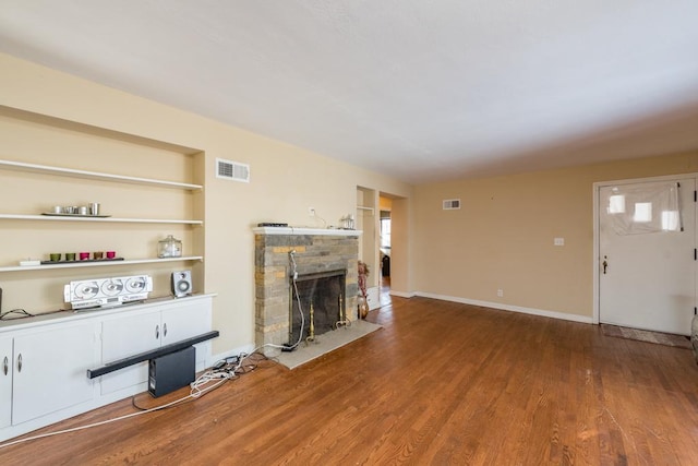 unfurnished living room featuring hardwood / wood-style flooring, built in features, and a fireplace