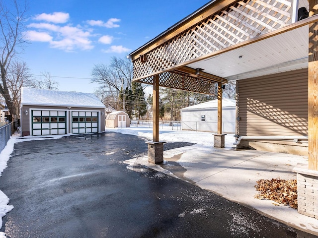 snow covered patio featuring a garage and a storage shed