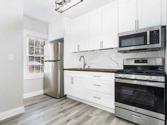 kitchen featuring backsplash, sink, stainless steel appliances, and white cabinetry