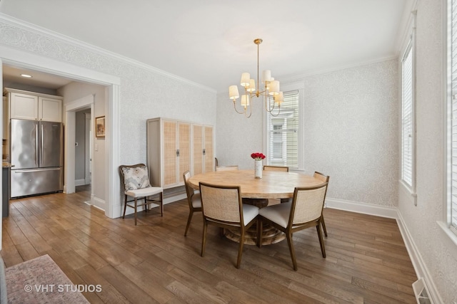 dining room featuring dark hardwood / wood-style flooring, crown molding, and an inviting chandelier