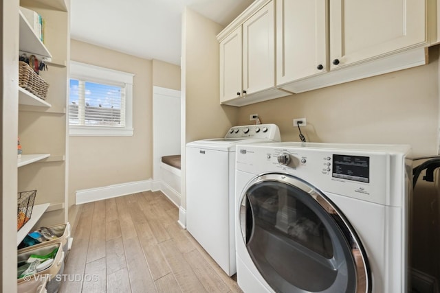 clothes washing area featuring cabinets, light wood-type flooring, and washing machine and clothes dryer