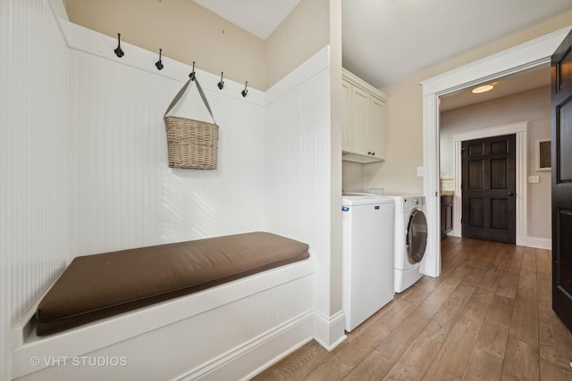 laundry room featuring light hardwood / wood-style floors, cabinets, and washer and clothes dryer