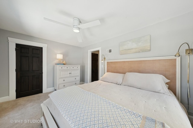 bedroom featuring light carpet, ceiling fan, and a walk in closet