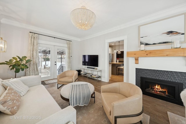 living room with a notable chandelier, dark hardwood / wood-style flooring, french doors, crown molding, and a tile fireplace