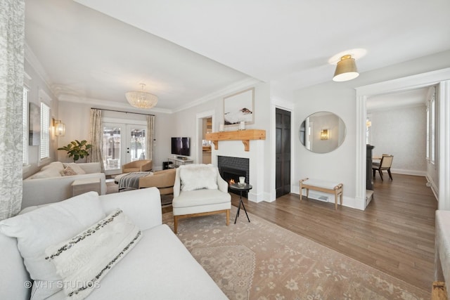 living room featuring dark wood-type flooring, ornamental molding, and an inviting chandelier